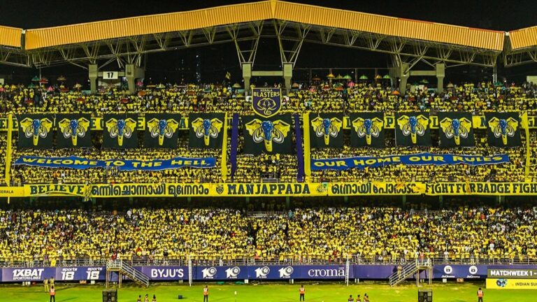 Massive crowd of Kerala Blasters FC fans, Manjappada, create a yellow wall with banners and flags in the stadium stands.